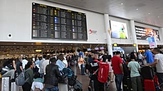 Viajantes aguardam informações em frente a um painel de partidas no Aeroporto Internacional de Bruxelas, em Bruxelas, a 19 de julho de 2024