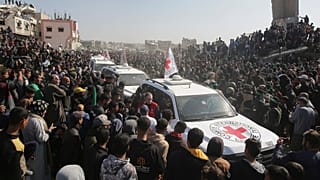 Folla circonda le auto della Croce Rossa mentre arrivano al luogo della consegna degli ostaggi thailandesi e israeliani a Khan Younis, nella Striscia di Gaza (30 gennaio 2025)