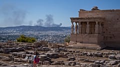 Una mujer posa para una foto delante de las estatuas cariátides que sostienen el pórtico del templo del Erecteión del siglo V a.C. en Atenas.