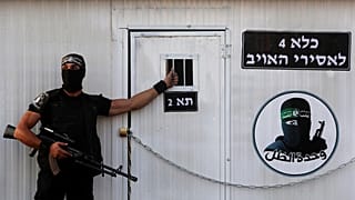 عنصر فلسطيني ملثم من كتائب عز الدين القسام، الجناح العسكري لحركة حماس، يقف أمام سجن وهمي لجنود إسرائيليين في مخيم رفح للاجئين في قطاع غزة، الأحد، 21 أغسطس، 2016