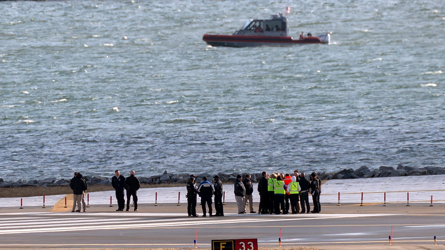 Officials gather at the end of runway 33 near the wreckage site in the Potomac River of a mid-air collision between an American Airlines jet and a Black Hawk helicopter