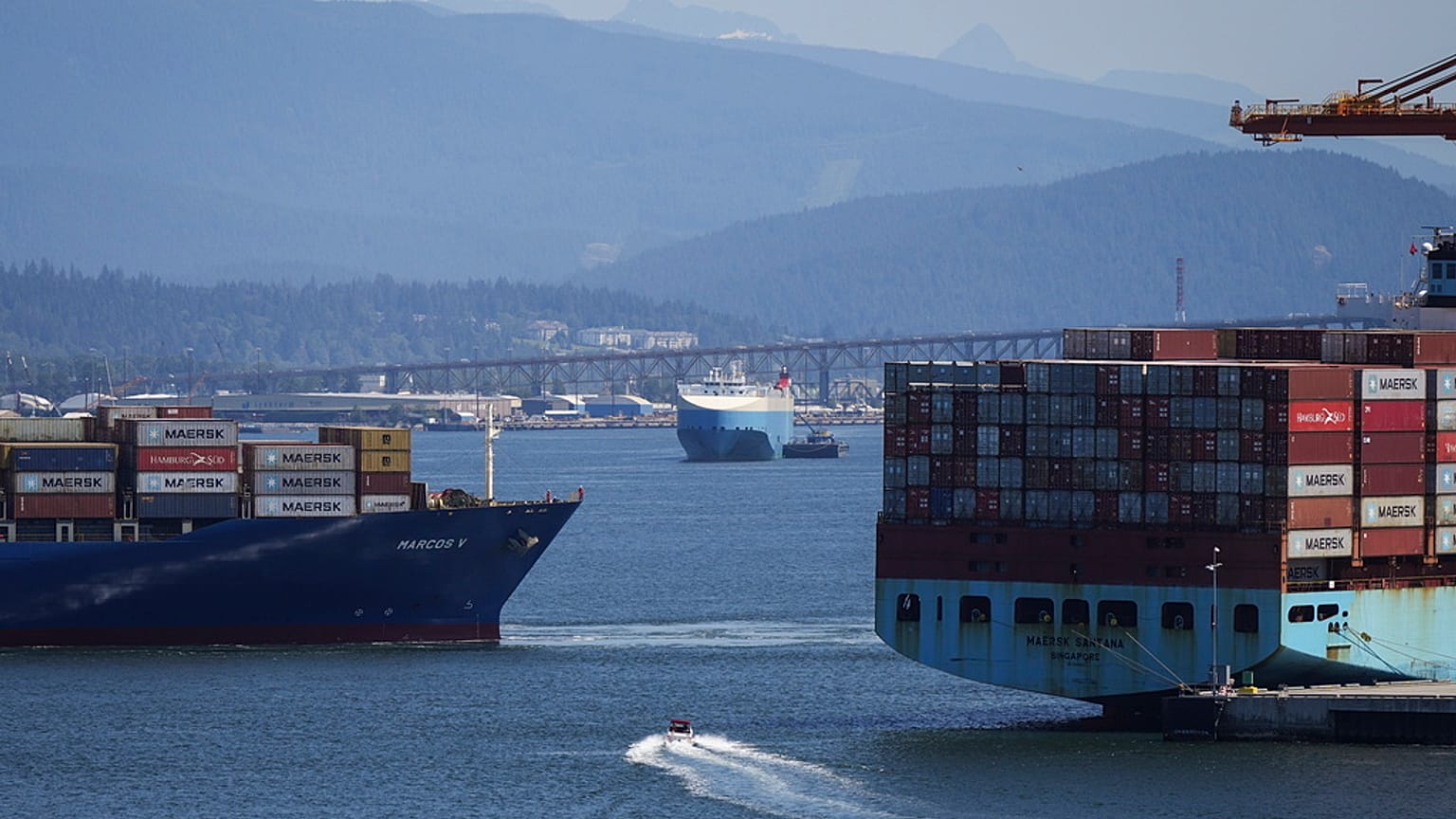 FILE - A boater passes between cargo ships on the harbour, in Vancouver, British Columbia, July 16, 2024. (Darryl Dyck/The Canadian Press via AP, File)