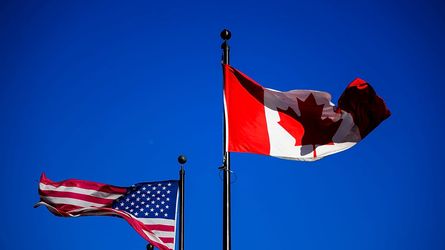 A bandeira dos EUA (à esquerda) e a bandeira do Canadá (à direita) são hasteadas lado a lado em Otava, no dia em que Trump anuncia os direitos aduaneiros