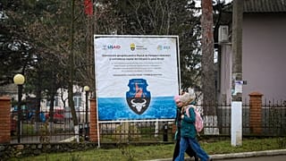 Des enfants passent devant une banderole présentant un projet soutenu par l'USAID en Moldavie, en janvier 2025.