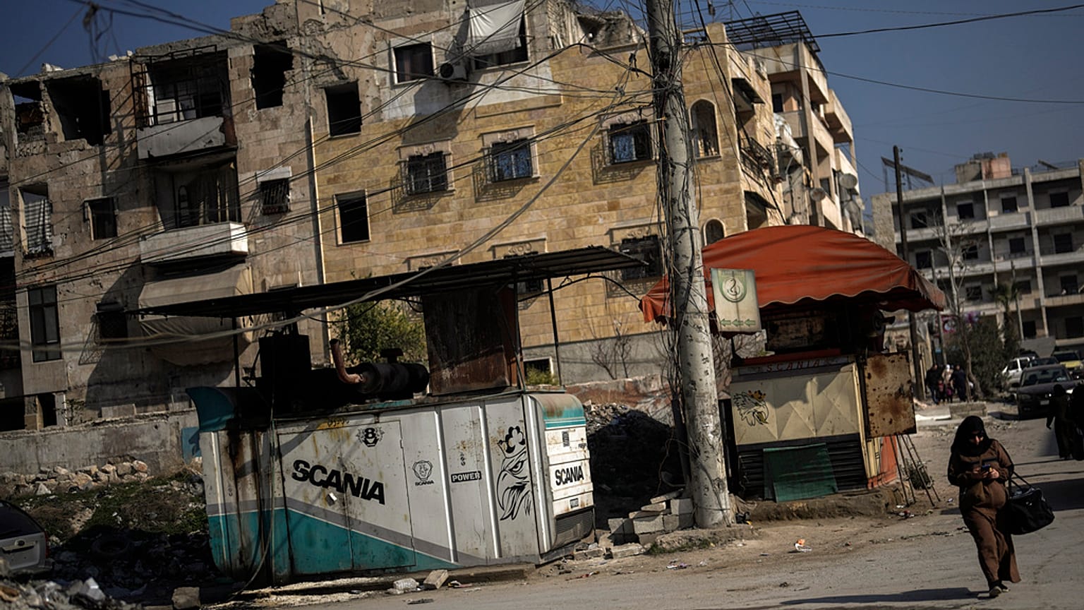 Kobieta idzie ulicą obok generatorów dostarczających prąd w mieście Aleppo w Syrii, czwartek, 30 stycznia 2025 r.