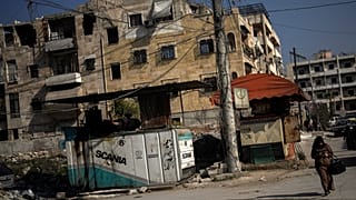 Kobieta idzie ulicą obok generatorów dostarczających prąd w mieście Aleppo w Syrii, czwartek, 30 stycznia 2025 r.
