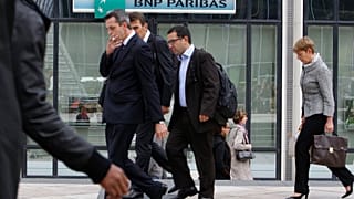 People walk past a logo of the BNP Paribas Bank at Paris business district La Defense, Tuesday, Sept. 20, 2011.