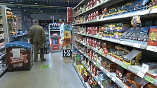 Un hombre está de pie en el pasillo mientras hace la compra en una tienda de comestibles en Serbia.