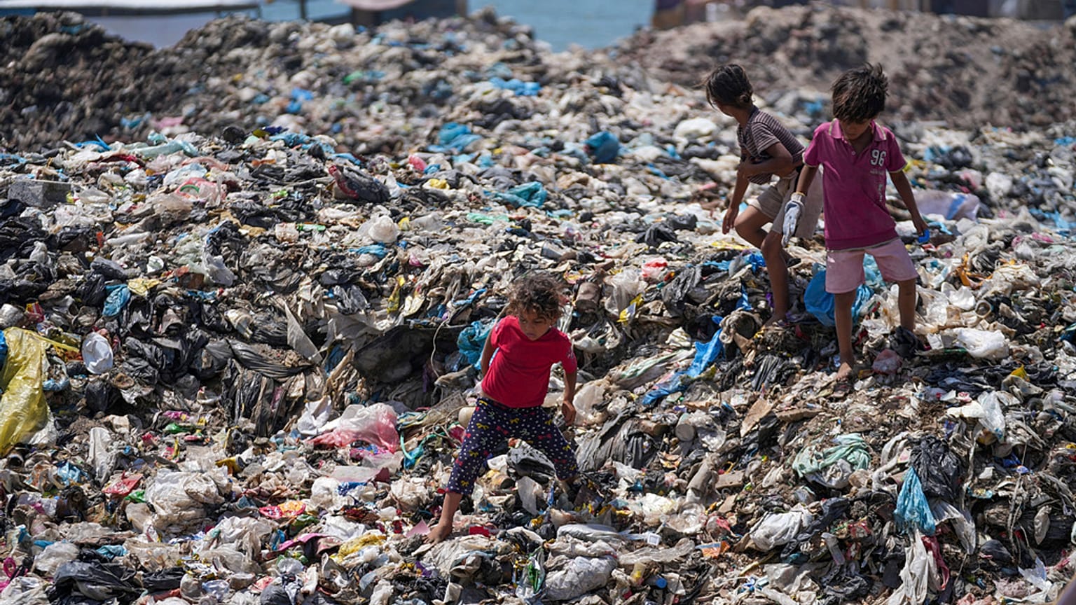 أطفال فلسطينيون يفرزون القمامة في مصب نفايات في مخيم النصيرات للاجئين في قطاع غزة، الخميس، 20 يونيو/حزيران 2024.