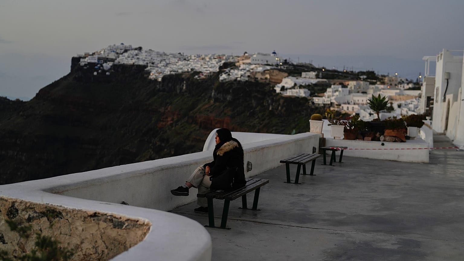 Bir turist, Yunan yetkililerin ülkenin güneyindeki popüler tatil adası Santorini'de yoğun sismik aktiviteye karşı acil önlemler alırken Firostefani'de oturuyor, 3 Şubat 2025.