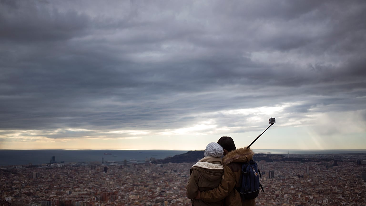 Una pareja observa la ciudad desde la cima de una montaña que sirvió como sitio estratégico para la defensa de Barcelona durante la Guerra Civil Española.