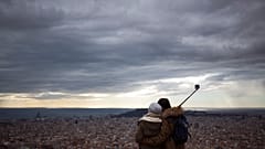 Una pareja observa la ciudad desde la cima de una montaña que sirvió como sitio estratégico para la defensa de Barcelona durante la Guerra Civil Española.