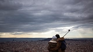 Una pareja observa la ciudad desde la cima de una montaña que sirvió como sitio estratégico para la defensa de Barcelona durante la Guerra Civil Española.