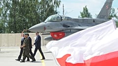 Polskie flagi narodowe powiewają przed myśliwcem F-16