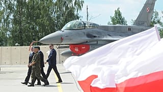 Polskie flagi narodowe powiewają przed myśliwcem F-16