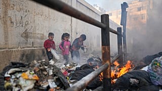 أطفال يلعبون بالورق على كومة قمامة محترقة في شوارع غزة، غزة، 4.02.2025