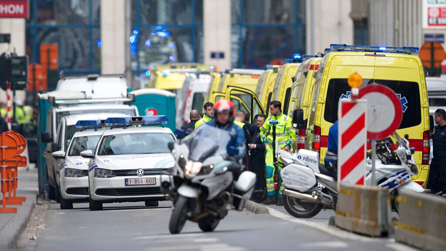 Ein Polizeimotorrad fährt nach einer Explosion in Brüssel am Dienstag, 22. März 2016, an Krankenwagen vorbei, die sich in der Nähe einer U-Bahn-Station aufhalten.