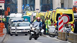 Ein Polizeimotorrad fährt nach einer Explosion in Brüssel am Dienstag, 22. März 2016, an Krankenwagen vorbei, die sich in der Nähe einer U-Bahn-Station aufhalten.