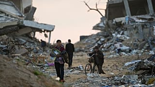 فلسطينيون يسيرون في أحد شوارع مدينة غزة المليئة بأنقاض المباني التي دمرت خلال الحرب، مدينة غزة، الثلاثاء 4 فبراير/شباط 2025