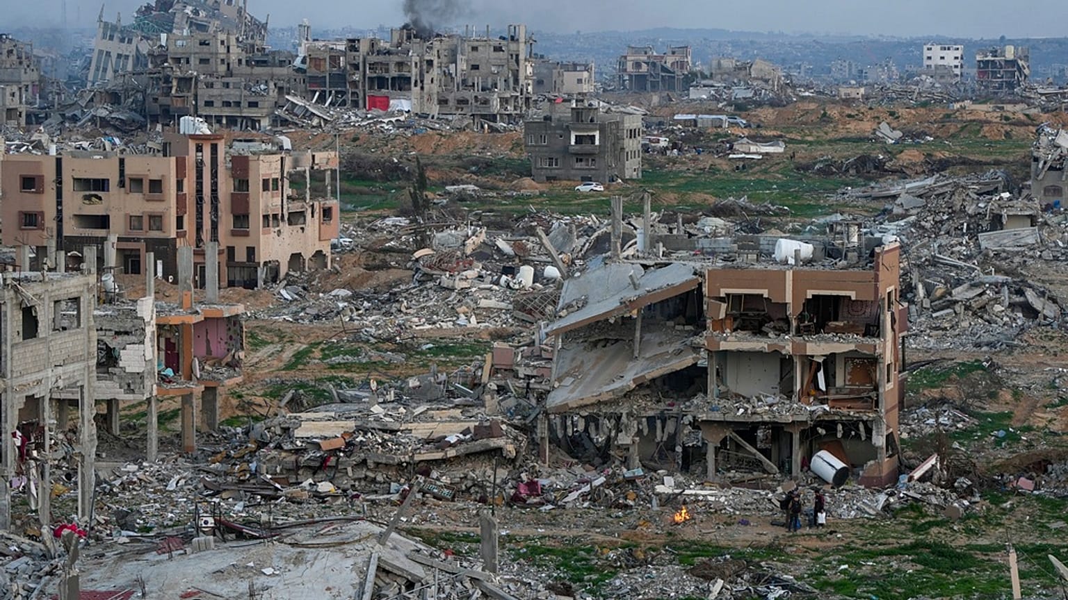 Les Palestiniens se tiennent près d'un feu à côté d'une maison détruite dans une zone jonchée de décombres de bâtiments détruits pendant l'offensive terrestre et aérienne de l