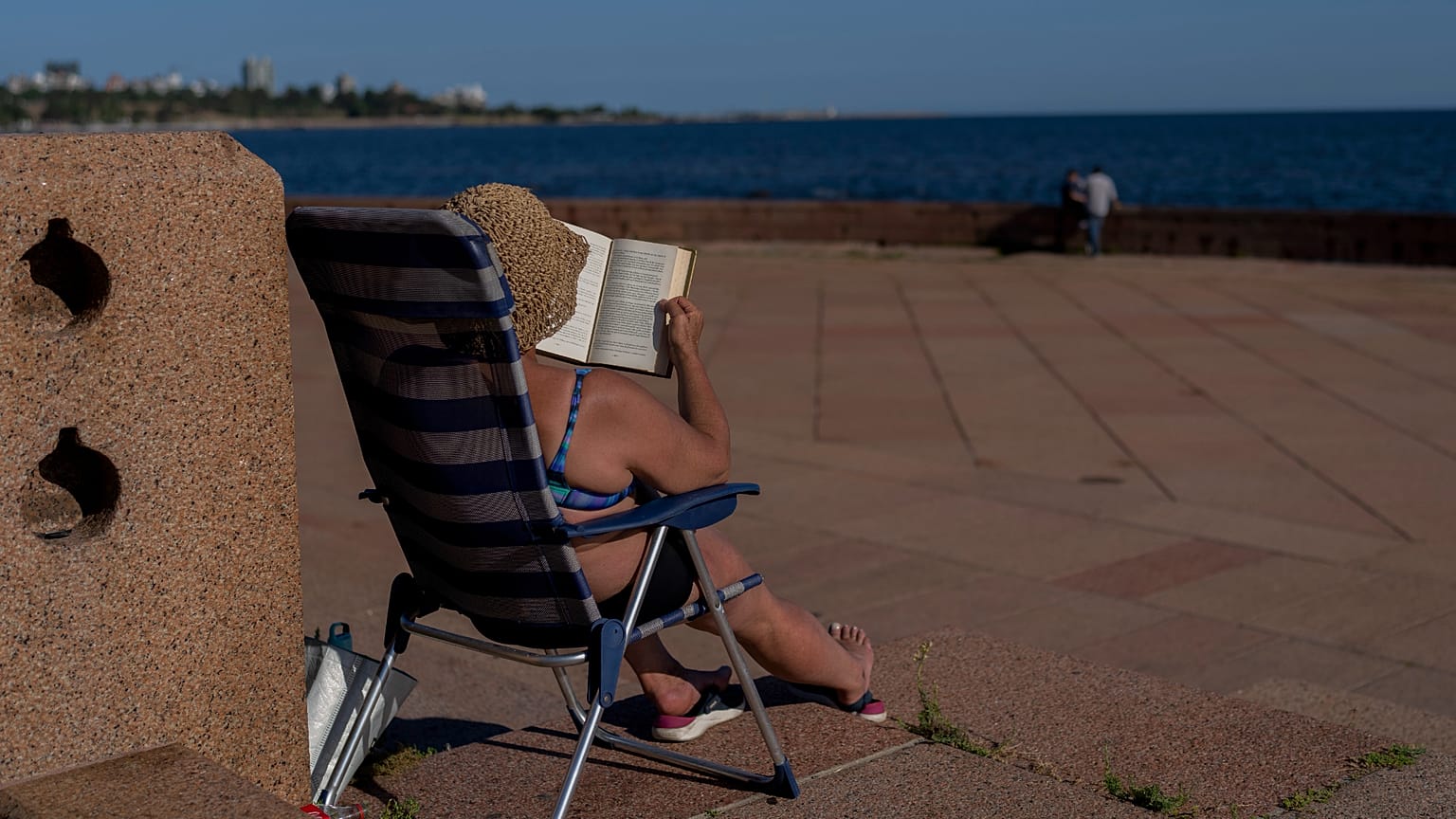 Женщина читает книгу, загорая в Монтевидео, Уругвай, 22 января 2025 г.