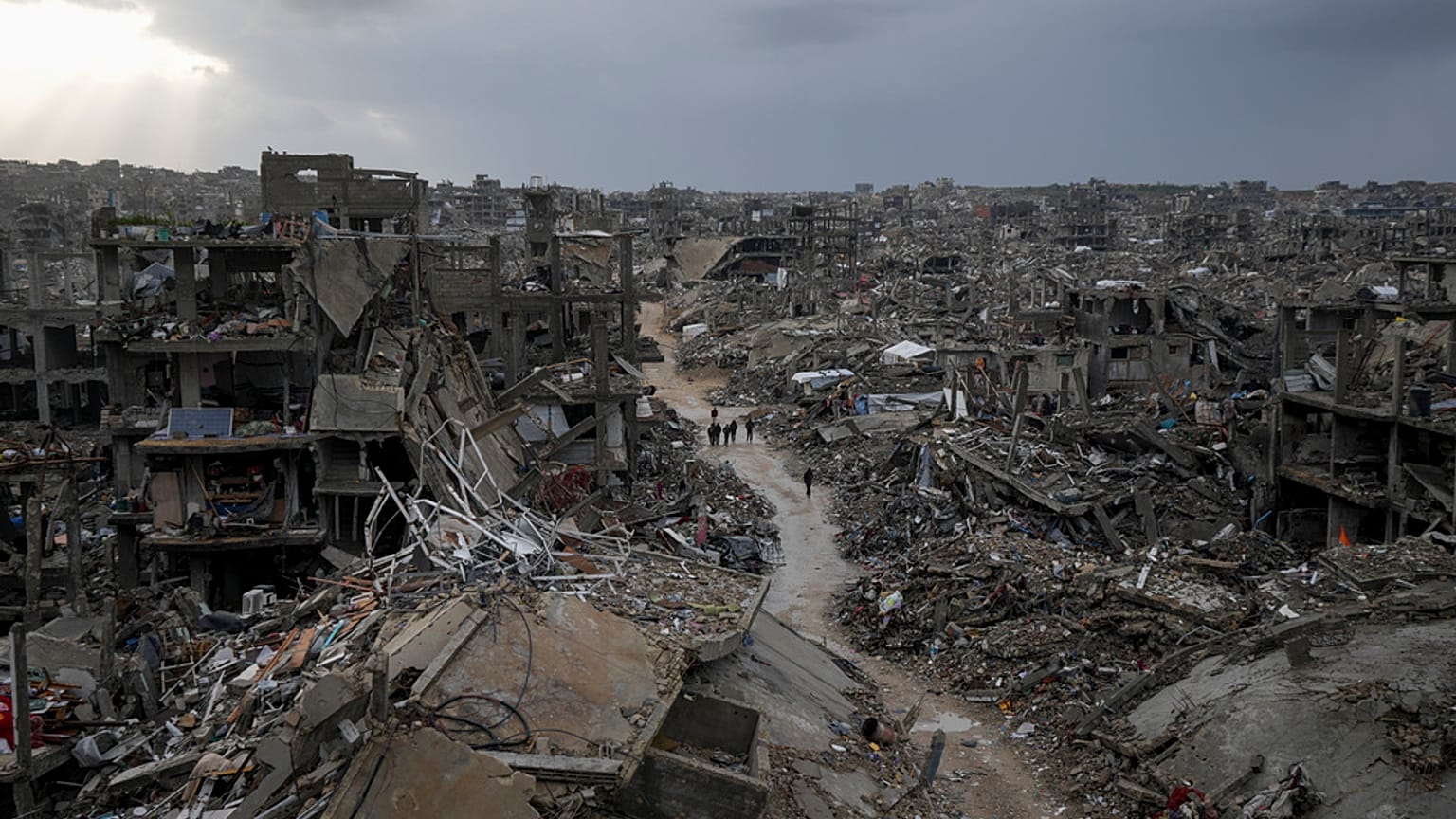 Ciudadanos palestinos caminan entre la devastación causada por una ofensiva aérea y terrestre israelí en la Franja de Gaza.