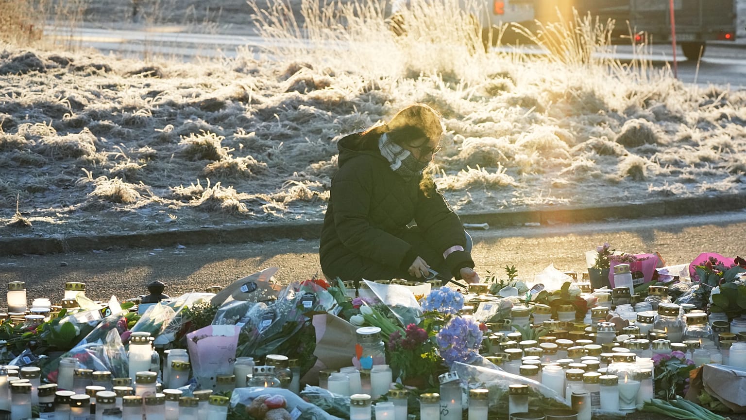 Женщина зажигает свечу у импровизированного мемориала рядом с образовательным центром для взрослых на окраине Эребру, Швеция, 6 февраля 2025 г.