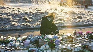 Женщина зажигает свечу у импровизированного мемориала рядом с образовательным центром для взрослых на окраине Эребру, Швеция, 6 февраля 2025 г.