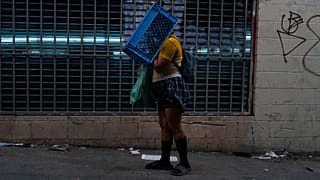 Uma mulher sem-abrigo com problemas de saúde mental caminha pelas ruas de Los Angeles com uma caixa na cabeça.