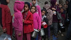 أطفال فلسطينيون يصطفون في مطبخ لتوزيع الطعام في دير البلح بقطاع غزة، الخميس 28 نوفمبر/تشرين الثاني 2024