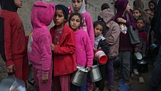 أطفال فلسطينيون يصطفون في مطبخ لتوزيع الطعام في دير البلح بقطاع غزة، الخميس 28 نوفمبر/تشرين الثاني 2024