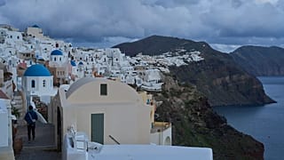 Bir turist, 4 Şubat 2025 Salı günü, depremden etkilenen Santorini adasındaki Oia kasabasında mavi kubbeli Ortodoks kiliselerine yaklaşıyor.