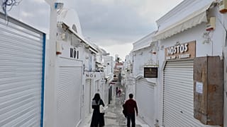 Turisti passano davanti a negozi chiusi nella città di Fira, isola di Santorini, Grecia, 3 febbraio 2025