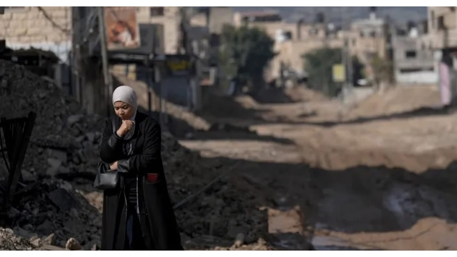 امرأة فلسطينية تسير على طريق مدمر جراء عملية عسكرية إسرائيلية استمرت ثلاثة أسابيع في مخيم جنين للاجئين بالضفة الغربية المحتلة.