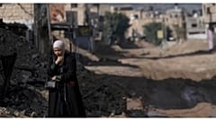 امرأة فلسطينية تسير على طريق مدمر جراء عملية عسكرية إسرائيلية استمرت ثلاثة أسابيع في مخيم جنين للاجئين بالضفة الغربية المحتلة.