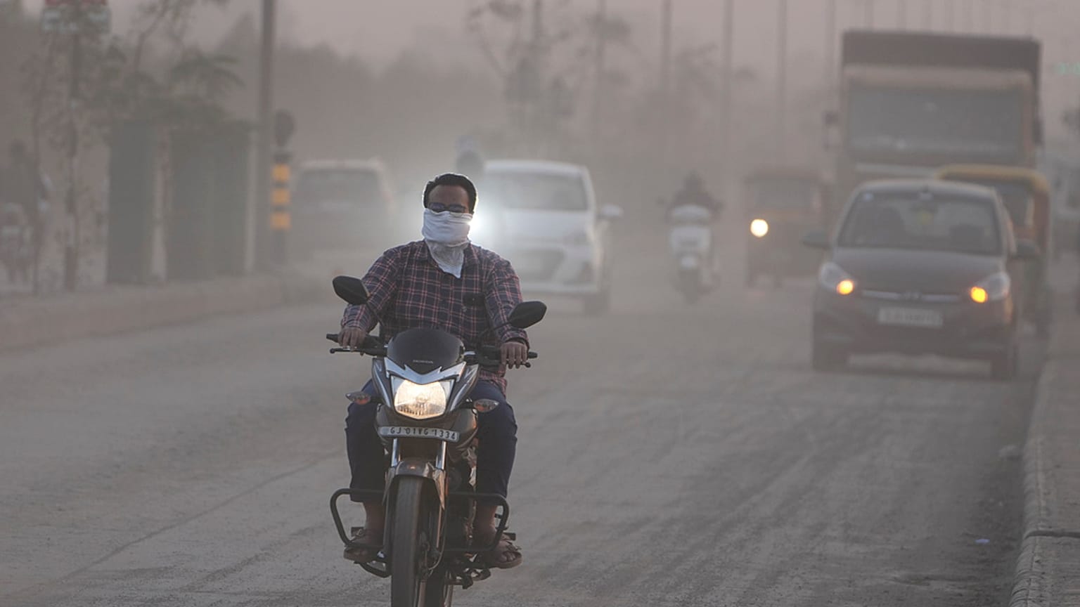 Imagen de un hombre con la cara cubierta mientras conduce su motocicleta, rodeado de aire contaminado en Ahmedabad, la India, el miércoles 5 de febrero de 2025.