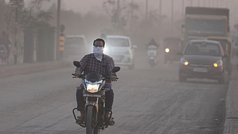 Imagen de un hombre con la cara cubierta mientras conduce su motocicleta, rodeado de aire contaminado en Ahmedabad, la India, el miércoles 5 de febrero de 2025.