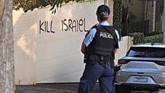 Bir polis memuru, Avustralya'nın Sidney kentinde bir duvara çizilen İsrail karşıtı grafitilere bakıyor, 11 Aralık 2024.
