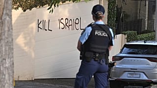 Bir polis memuru, Avustralya'nın Sidney kentinde bir duvara çizilen İsrail karşıtı grafitilere bakıyor, 11 Aralık 2024.