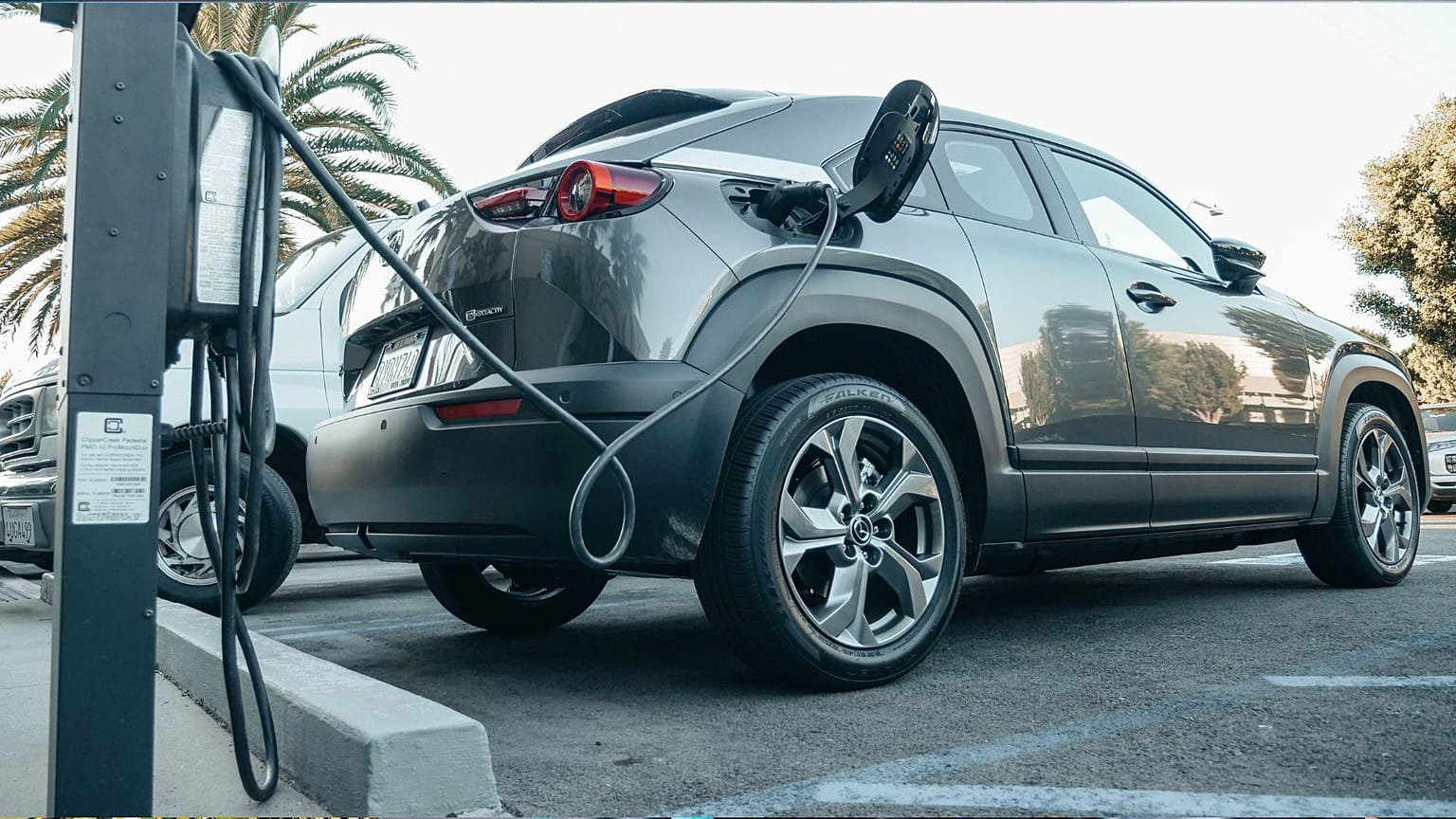 Automóvel elétrico cinzento estacionado num posto de carregamento.