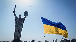 Un dron porta una gran bandera nacional frente al Monumento a la Patria de Ucrania en Kiev, Ucrania, miércoles 24 de agosto de 2022.