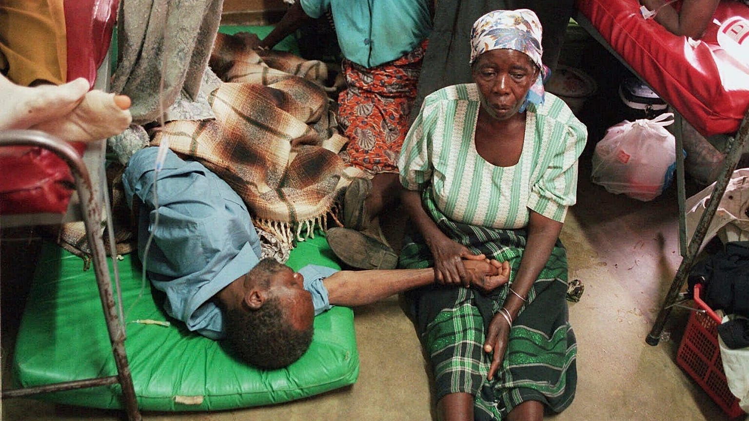 ARQUIVO - Uma mulher segura a mão de um familiar doente deitado no chão do superlotado Hospital Central de Lilongwe, em Lilongwe, no Malawi.