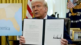 President Donald Trump holds up a signed executive order in the Oval Office of the White House, Thursday, Feb. 13, 2025, in Washington.