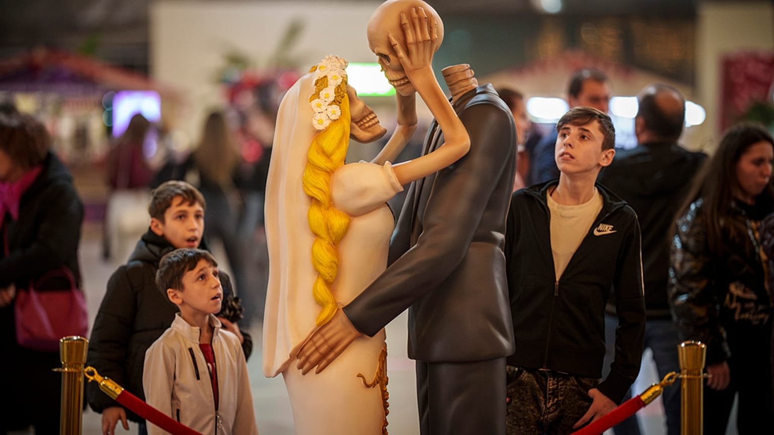 Des gens regardent un couple de squelettes s'embrasser dans une installation baptisée "Jusqu'à ce que la mort nous sépare" lors d'un événement de la Saint-Valentin à Bucarest, en Roumanie, le mardi 13 février 2024. (AP Photo
