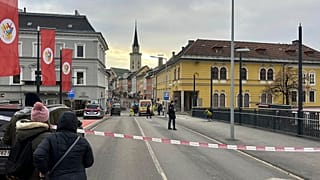 Menschen schauen in ein abgesperrtes Gebiet, in dem ein 23-jähriger Mann in der südösterreichischen Stadt Villach mehrere Menschen niedergestochen hat, Samstag, 15. Februar 2025