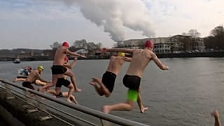 Nadadores lanzándose a las aguas del río Mosa en Huy, Bélgica, el domingo 16 de febrero de 2025.