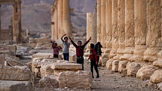 أطفال يلعبون ويرفع أحدهم علامة النصر في مدينة تدمر الأثرية في سوريا