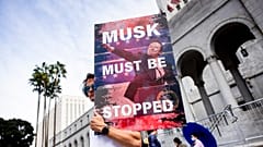 Un manifestante sostiene un póster de Elon Musk durante una concentración para protestar contra las políticas del presidente Trump en el Día de los Presidentes este lunes