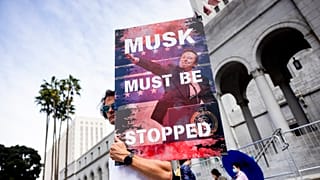 A demonstrator holds a poster of Elon Musk during a rally to protest President Trump's policies on Presidents Day on Monday