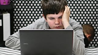 Un adolescente leyendo con su portátil